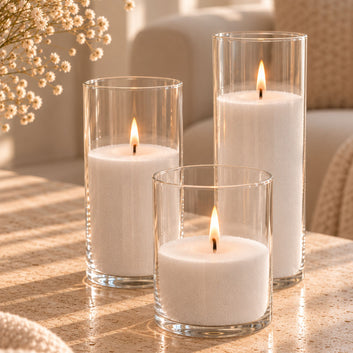 Set of 3 clear glass cylinder vases filled with white FLAMMÉ Candle Dust and lit wicks, styled on a coffee table